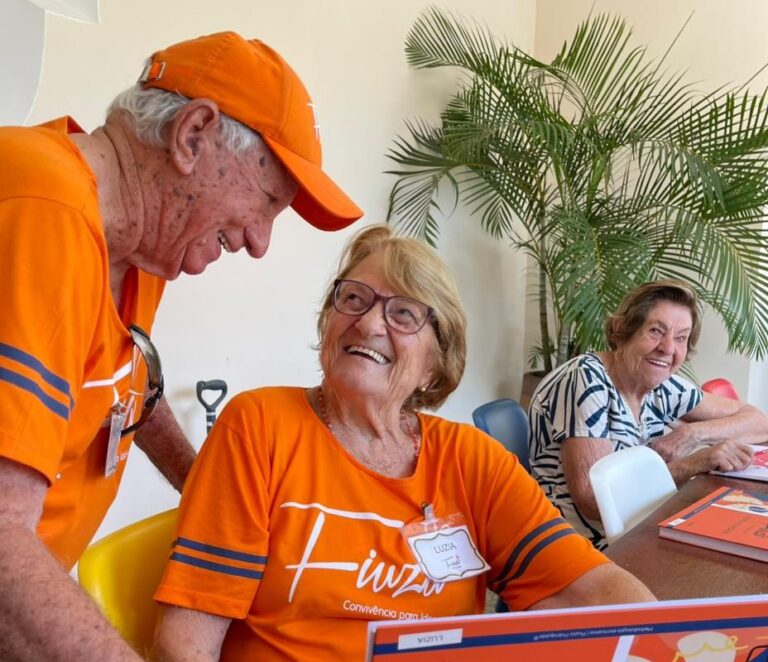 Idosos participam de uma atividade em grupo usando camisetas laranjas da Fiuza.
